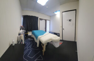 View of massage office, massage table covered with sheets, doors, curtained window. This is the office for Human Touch Marin - clean, sanitary, warm, and ready for you. 